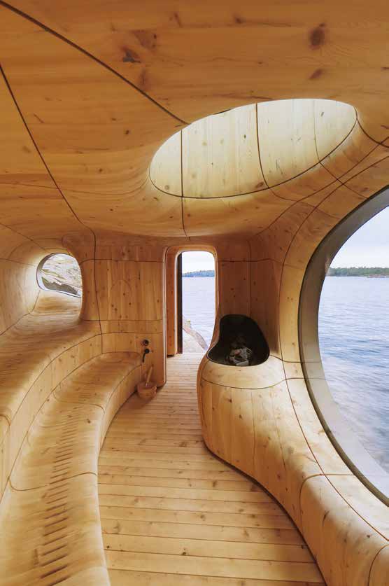A portrait view of the same carved cedar chamber, a bench curling beneath one oval window while a second opening looks through to the lake.